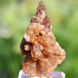 Könnte beinhalten: Ein Cluster aus braunen, durchscheinenden Kristallen mit einer rauen, strukturierten Oberfläche. Die Kristalle sind in einer spitzen, unregelmäßigen Form angeordnet, die an einen kleinen Berg erinnert.