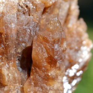 Könnte beinhalten: Nahaufnahme eines Clusters aus braunen Quarzkristallen mit einem spitzen Kristall in der Mitte.