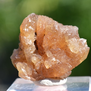 Könnte beinhalten: Ein Cluster aus durchscheinenden, bernsteinfarbenen Kristallen mit einer rauen, strukturierten Oberfläche. Die Kristalle sind in einer natürlichen Formation zusammengefügt und bilden ein einzigartiges und interessantes Stück.