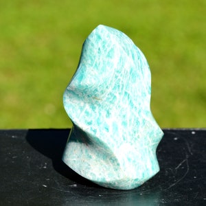 Peut inclure: Un cristal d'amazonite sculpté vert et blanc en forme de flamme. Le cristal a une surface lisse et polie.