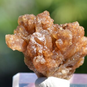 Könnte beinhalten: Ein Cluster aus braunen, durchscheinenden Kristallen mit einer rauen, strukturierten Oberfläche. Die Kristalle sind in einem zufälligen, organischen Muster angeordnet, was eine einzigartige und interessante Darstellung ergibt.