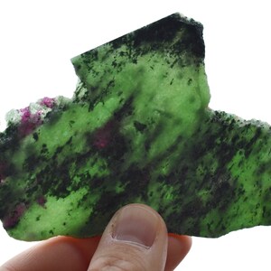 Peut inclure: Une pierre précieuse de zoïsite verte et noire avec des inclusions roses. La pierre est de forme irrégulière et a une texture rugueuse et naturelle.