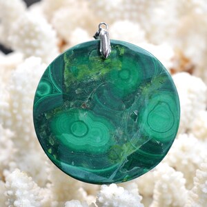 May include: A round green malachite pendant with a silver bail. The malachite has a swirling pattern of green and brown.
