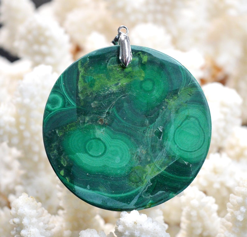 May include: A round green malachite pendant with a silver bail. The malachite has a swirling pattern of green and brown.