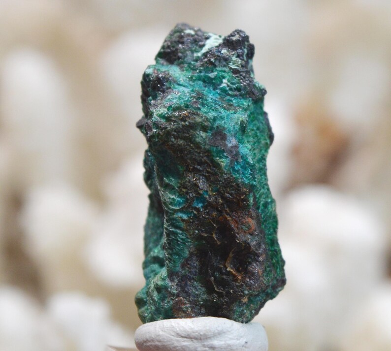 May include: A rough, dark green and black mineral specimen with a unique, irregular shape.