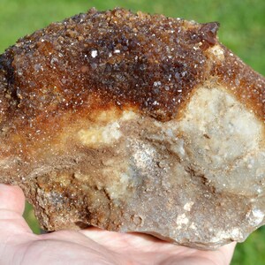 Könnte beinhalten: Ein großer, rauer, brauner und weißer Stein mit einem Cluster aus kleinen, klaren Quarzkristallen auf der Oberseite.