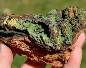 May include: A close-up of a rock with green and brown layers. The rock has a rough, textured surface.
