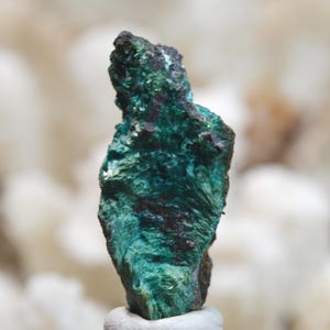 May include: A green and black mineral specimen with a rough, textured surface.