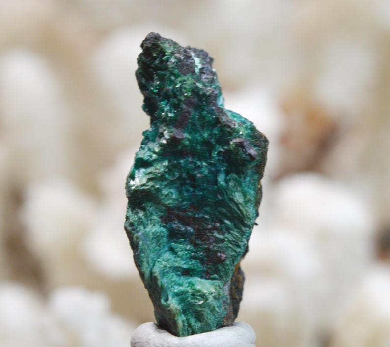 May include: A green and black mineral specimen with a rough, textured surface.