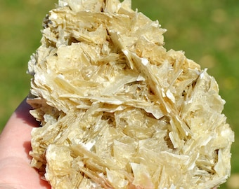 May include: A large, light brown selenite crystal cluster with a rough, textured surface. The crystal is made up of many thin, layered pieces that create a unique and interesting pattern.