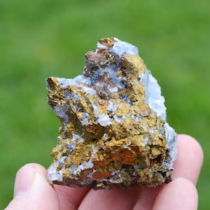Peut inclure: Une roche rugueuse de couleur dorée avec des cristaux blancs incrustés. La roche a une forme naturelle irrégulière.