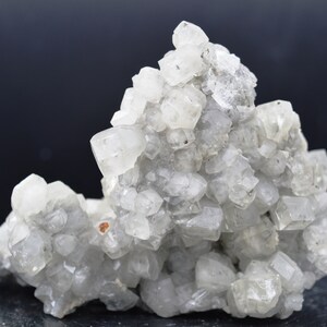 Puede incluir: Un grupo de cristales de calcita blancos con una superficie rugosa y texturizada. Los cristales est&aacute;n agrupados en una formaci&oacute;n natural, creando una exhibici&oacute;n &uacute;nica e interesante.