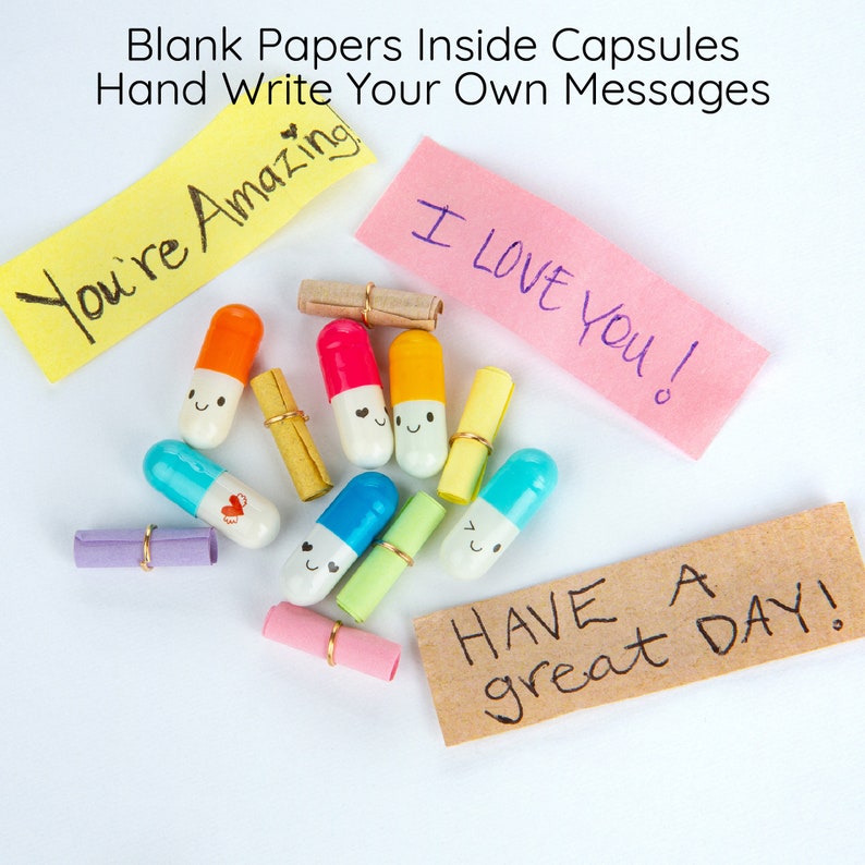 Pode incluir: C&aacute;psulas coloridas com rostos felizes cont&ecirc;m pap&eacute;is em branco para escrever mensagens. As c&aacute;psulas est&atilde;o espalhadas sobre uma superf&iacute;cie branca com notas adesivas coloridas que dizem "You're Amazing", "I Love You!" e "Have a great Day!"