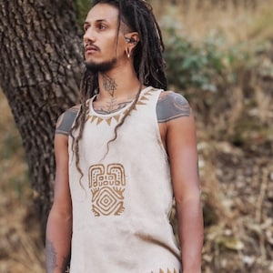 Puede incluir: Una camiseta beige sin mangas con un diseño geométrico marrón en la parte delantera. La camiseta tiene un ribete marrón alrededor del cuello y el dobladillo inferior.