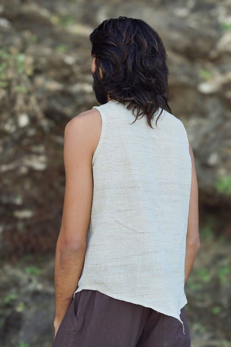 May include: A sleeveless, off-white linen top with a slightly asymmetrical hem. The top is made of a lightweight, breathable fabric and has a relaxed fit.