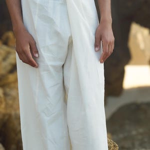 May include: White cotton pants with a wrap-around style, worn by a person standing on a rocky surface.
