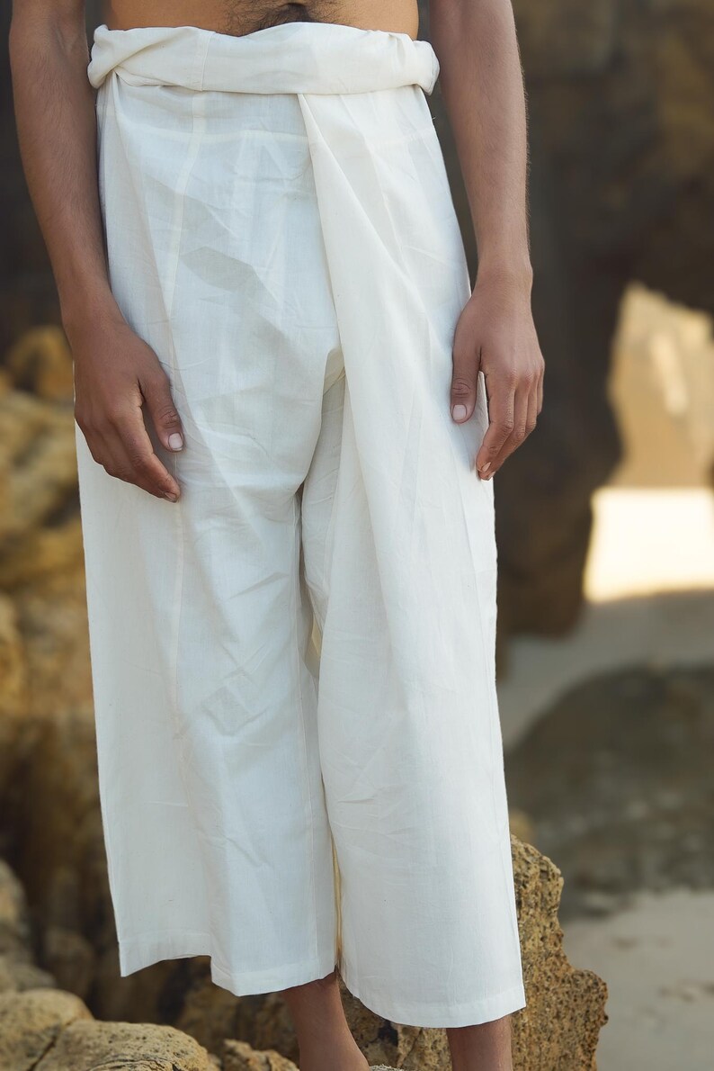May include: White cotton pants with a wrap-around style, worn by a person standing on a rocky surface.