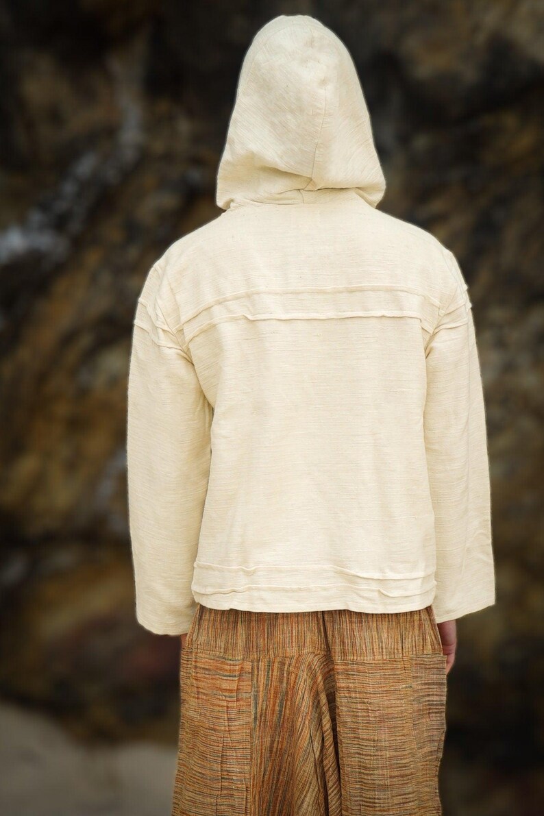 May include: A cream-colored hooded sweatshirt with long sleeves and a relaxed fit. The sweatshirt has a simple design with a single seam down the back.