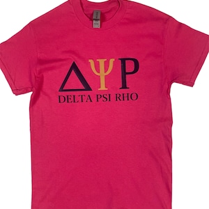 May include: A pink t-shirt with the Greek letters Delta, Psi, and Rho in navy blue, gold, and navy blue, respectively. The words DELTA PSI RHO are printed below the letters in navy blue. The shirt is made of a soft material.