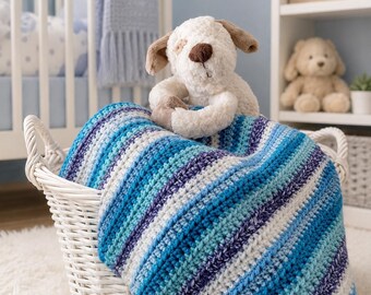 May include: A white woven basket containing a crocheted blanket with horizontal stripes in shades of blue, teal, and white. A plush cream-colored dog toy with brown ears and a brown nose sits on top of the folded blanket inside the basket.