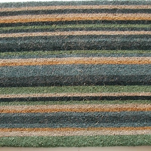 May include: A brown, green, and beige striped doormat made of natural fibers.