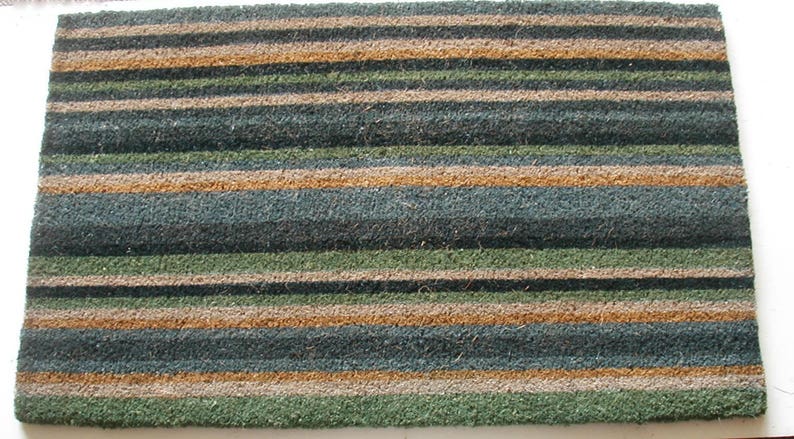 May include: A brown, green, and beige striped doormat made of natural fibers.