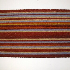 May include: A brown doormat with horizontal stripes in shades of blue, beige, and orange.