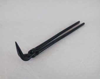 May include: Black metal blacksmith tongs with a curved hook on one end.