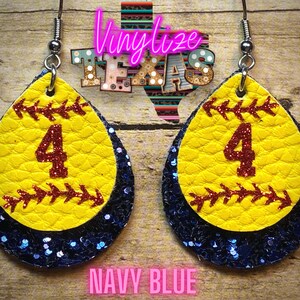 K&ouml;nnte beinhalten: Ein Paar Softball-Ohrringe mit einem gelben Softball mit einer roten Nummer 4 und einem marineblauen Glitzer-Hintergrund. Die Ohrringe sind tropfenf&ouml;rmig.