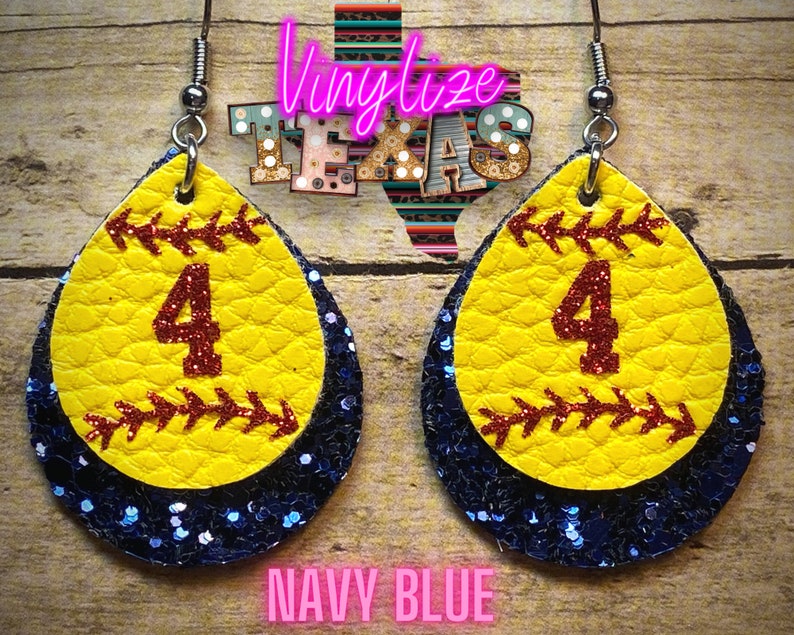 K&ouml;nnte beinhalten: Ein Paar Softball-Ohrringe mit einem gelben Softball mit einer roten Nummer 4 und einem marineblauen Glitzer-Hintergrund. Die Ohrringe sind tropfenf&ouml;rmig.