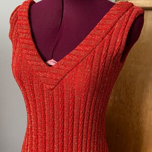 May include: A red sleeveless dress with gold glitter. The dress has a V-neck and a ribbed texture.
