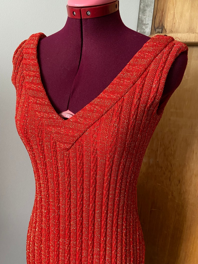 May include: A red sleeveless dress with gold glitter. The dress has a V-neck and a ribbed texture.