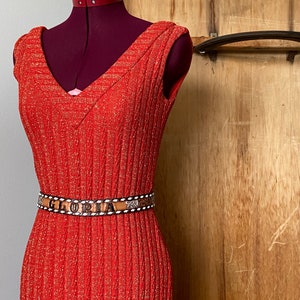May include: A red sleeveless dress with a sparkly texture and a brown belt with the word "GLORIA" embossed on it.
