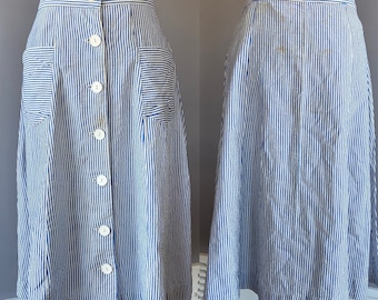 May include: A blue and white striped skirt with a button-up front and two pockets. The skirt is knee-length and has a flared silhouette.
