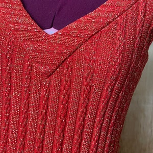 May include: A red sleeveless dress with a V-neck and a sparkly texture.