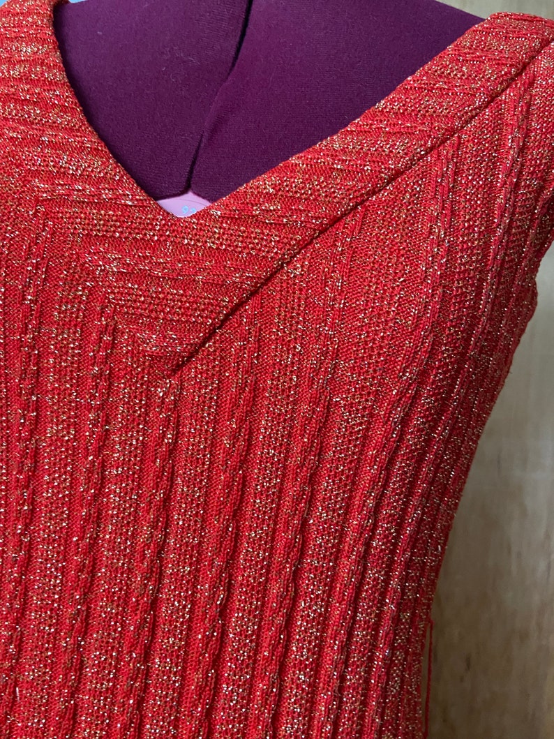May include: A red sleeveless dress with a V-neck and a sparkly texture.