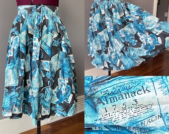 May include: A blue and black vintage skirt with a print of "The American Almanack 1753". The skirt is full and has a gathered waist.