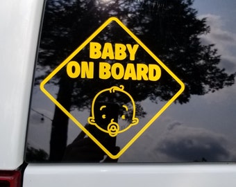 May include: Yellow and black car sticker with the text "BABY ON BOARD" and a cartoon baby face.
