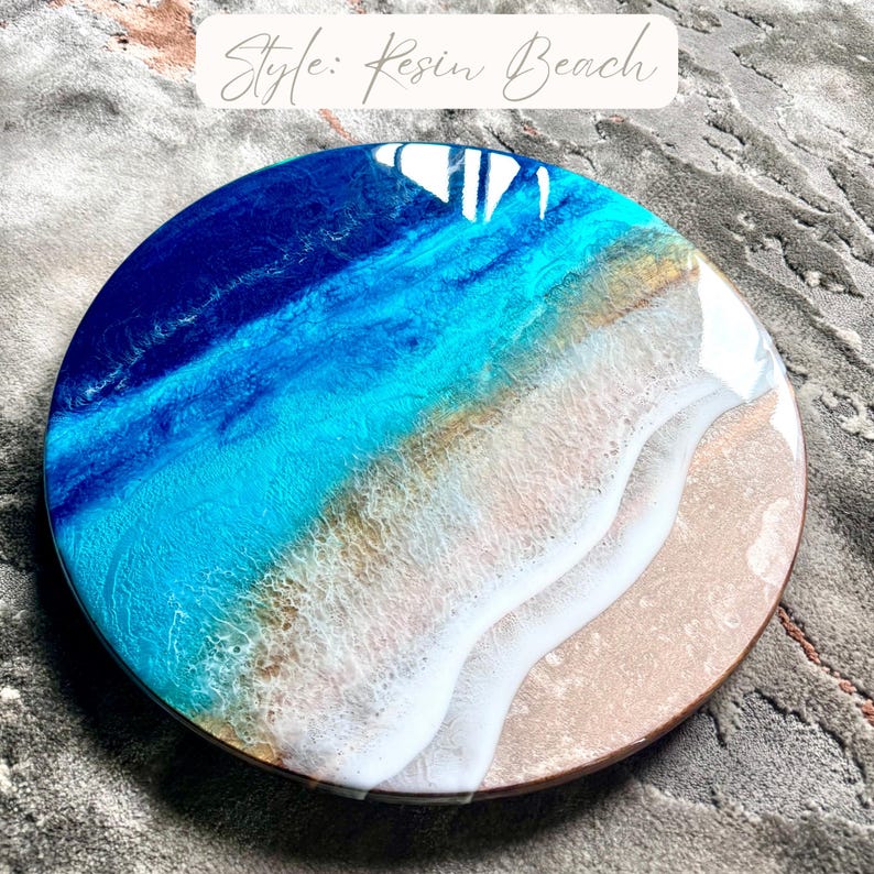 May include: Circular resin artwork depicting a beach scene. It features layers of blue, turquoise, and white resin, resembling ocean waves and a sandy beach. The piece has a wooden edge and the text "Style: Resin Beach".