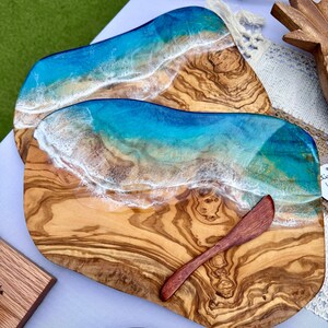 Pode incluir: Uma t&aacute;bua de servir de madeira com um design de onda de oceano de resina azul e branca. A t&aacute;bua tem uma veia de madeira natural e vem com uma pequena faca de manteiga de madeira.