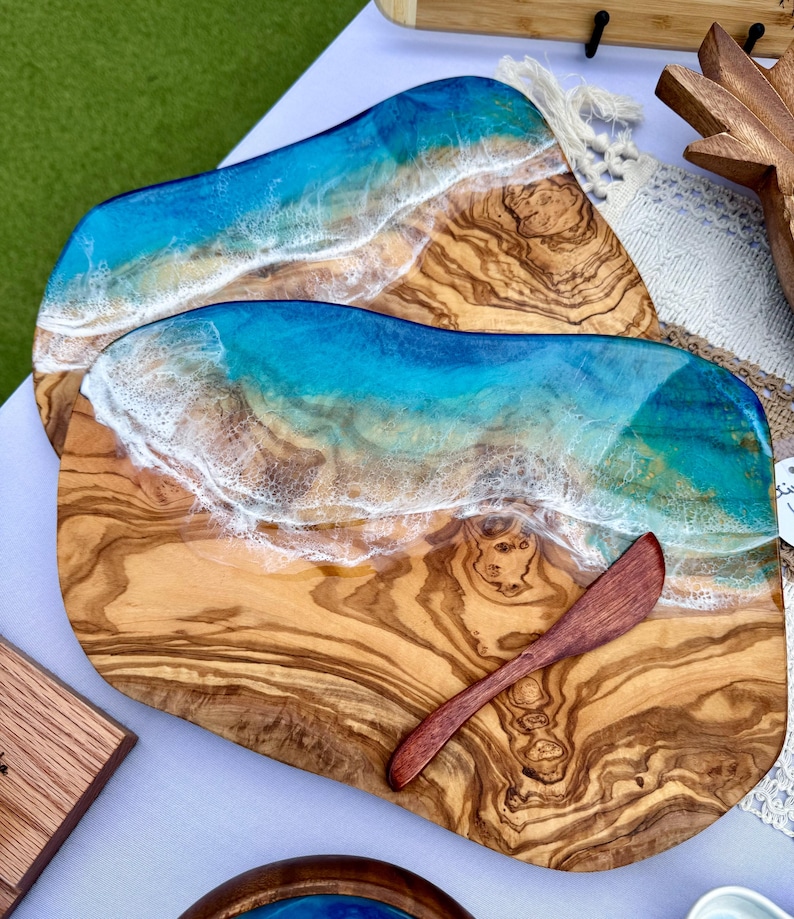 Pode incluir: Uma t&aacute;bua de servir de madeira com um design de onda de oceano de resina azul e branca. A t&aacute;bua tem uma veia de madeira natural e vem com uma pequena faca de manteiga de madeira.