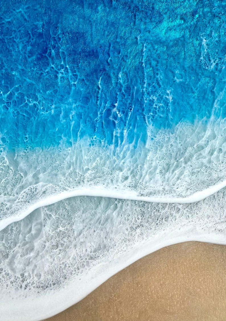 May include: Abstract artwork of a beach scene. The image shows a gradient of colours, from deep blue to light blue, representing the ocean. White foamy waves meet a tan sandy shore. The artwork evokes a sense of tranquility and the beauty of nature.