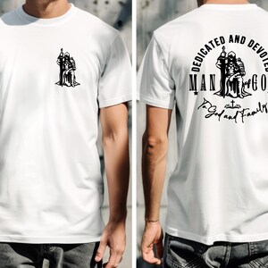 May include: White t-shirt with a black graphic on the front and back. The front graphic is a silhouette of a person holding a staff. The back graphic reads "DEDICATED AND DEVOTED MAN OF GOD To God and Family."
