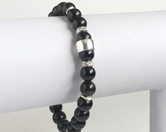 Puede incluir: Pulsera de cuentas negras con un acento plateado y diamantes de imitación transparentes.