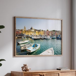May include: A wooden cabinet with a woven rattan door and three drawers. The cabinet is in front of a window with white curtains and a view of a harbor with boats. The image also includes a glass coffee table with a book and a glass on top.