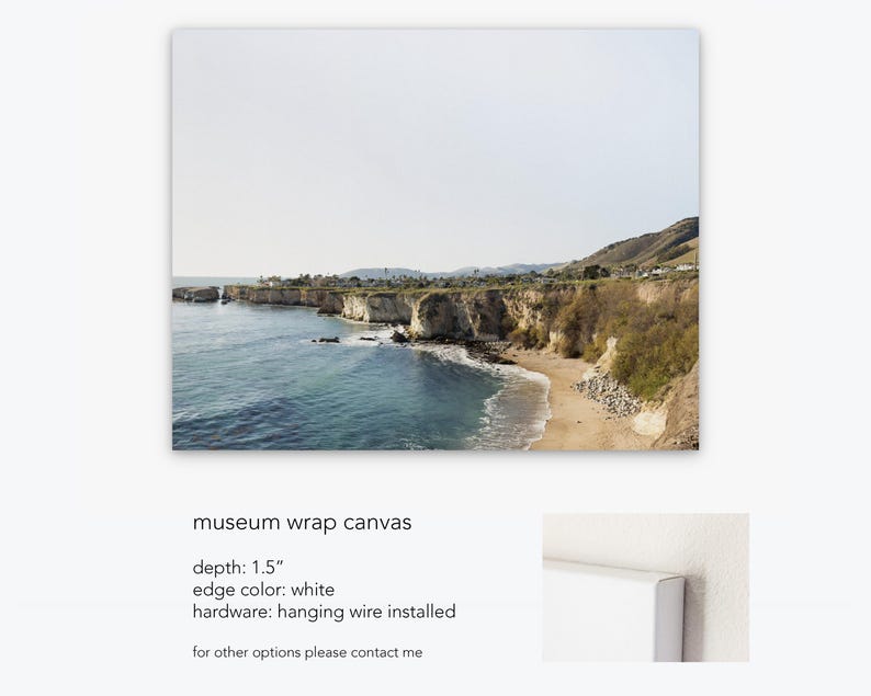 May include: A canvas print of a coastal landscape with a rocky cliffside and a sandy beach. The print has a 1.5 inch depth, white edges, and hanging wire installed.