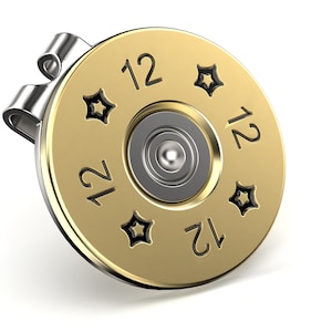 May include: A gold-colored golf ball marker shaped like a 12 gauge shotgun shell with a silver clip. The shell has the number "12" printed on it four times and four star-shaped designs.