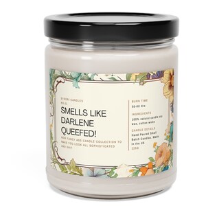 May include: A white candle jar with a floral design label. The label reads "Smells Like Darlene Queefed!" and includes details about the candle, such as burn time, ingredients, and size. The candle is 225 grams.
