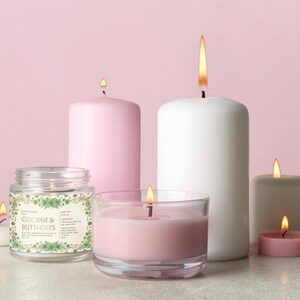 Może przedstawiać: Kolekcja zapalonych świec w r&oacute;żnych rozmiarach i kształtach, w tym świeca w słoiku z napisem "COCAINE & BUTTHOLES". Świece są w odcieniach r&oacute;żu, bieli i szarości, z płomieniami na r&oacute;żowym tle.