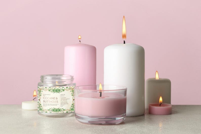 Może przedstawiać: Kolekcja zapalonych świec w r&oacute;żnych rozmiarach i kształtach, w tym świeca w słoiku z napisem "COCAINE & BUTTHOLES". Świece są w odcieniach r&oacute;żu, bieli i szarości, z płomieniami na r&oacute;żowym tle.